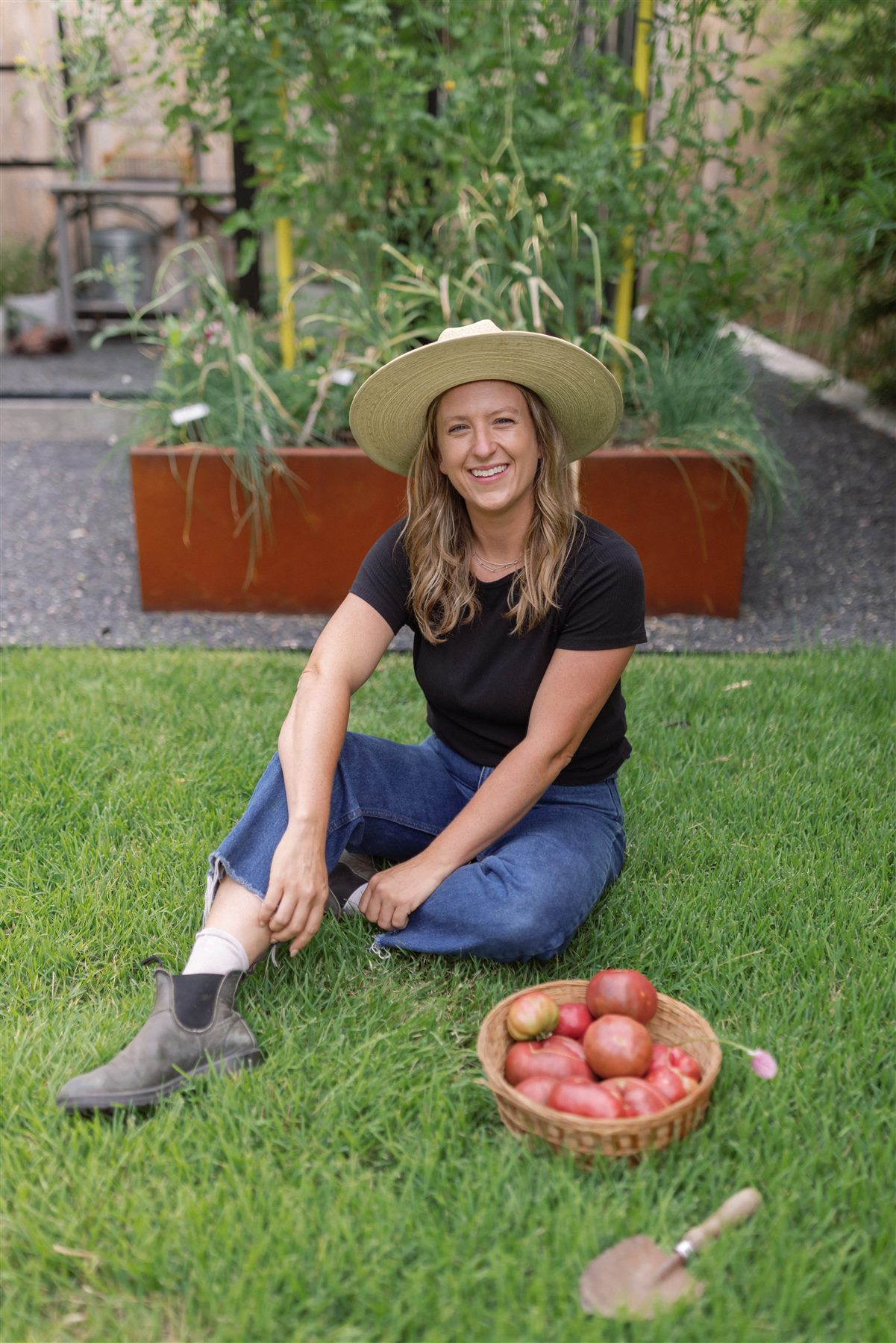 Founder sitting in the garden with a basket of tomatoes
